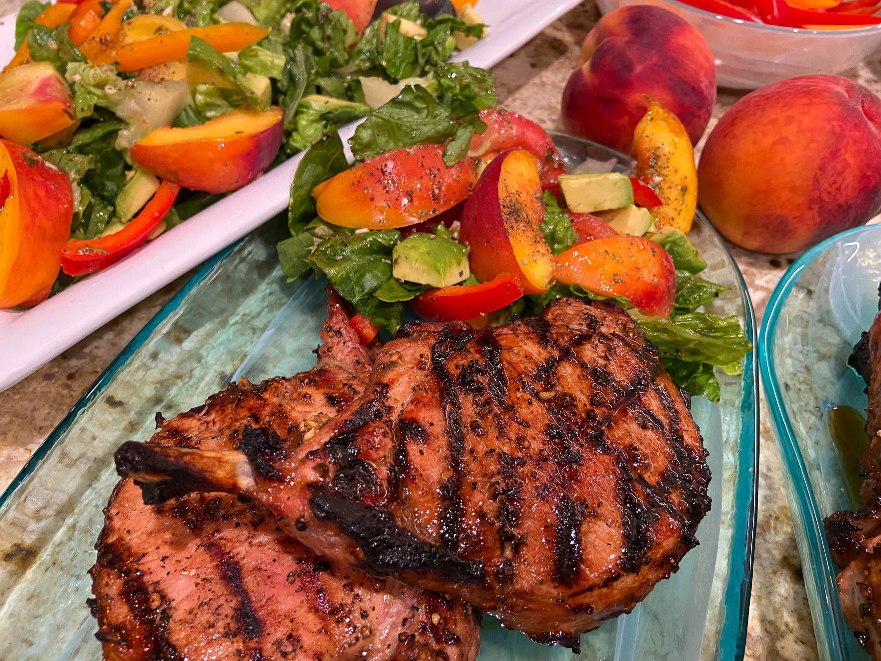 Grilled peach pork chops served with fresh peach salad and avocado, a summer grilling recipe from Food Style Uncorked.